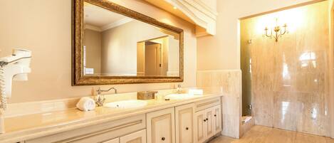 A bathroom with a large mirror, two sinks, and a vanity with drawers.