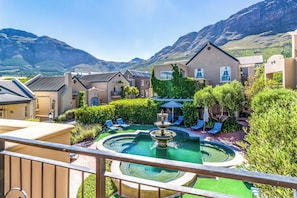 A hotel courtyard with a swimming pool, lounge chairs, and a fountain. - L'ermitage - Franschhoek Chateau & Villas (Franschhoek)