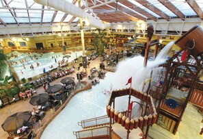 Een overdekt waterpark met een groot zwembad, verschillende glijbanen en zitgedeeltes.