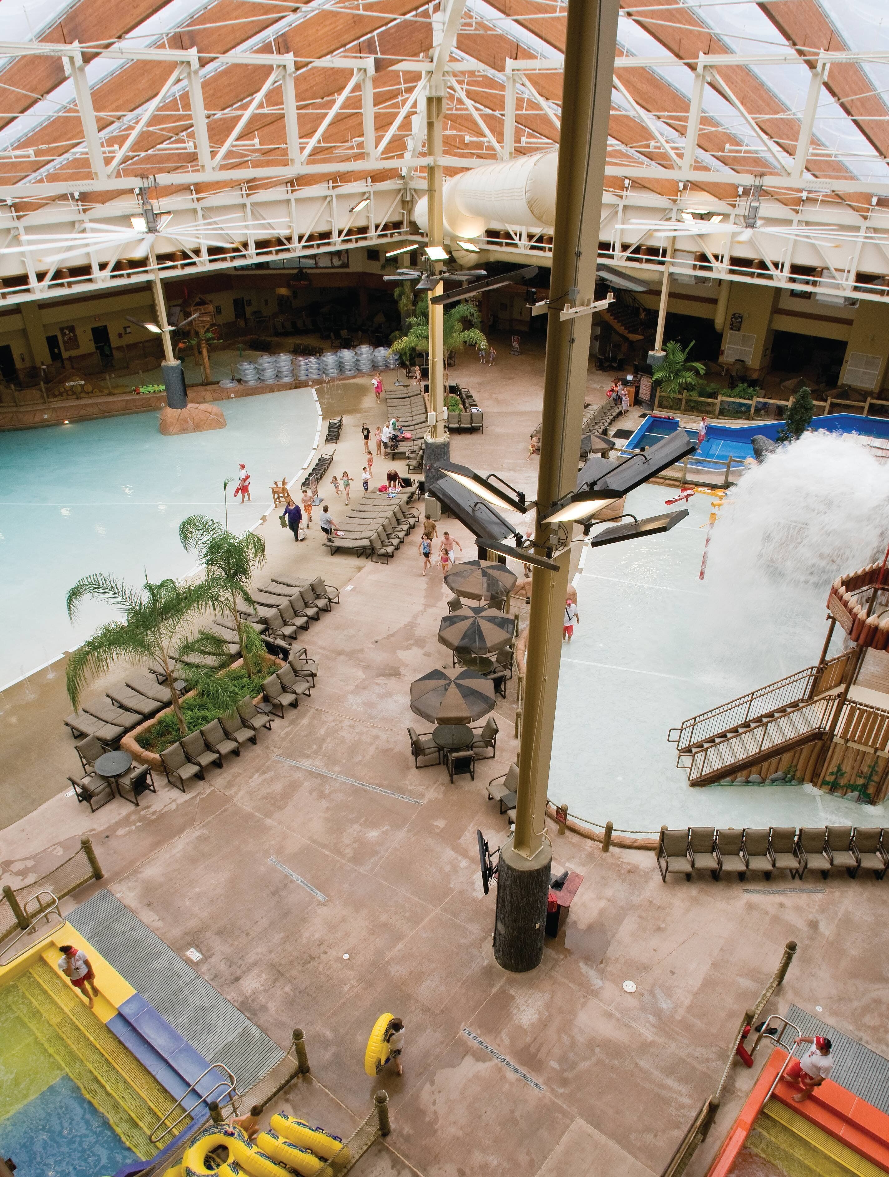 Un parque acuático interior con piscina, toboganes y zonas de descanso.