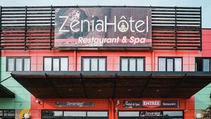 A building with a sign reading "ZeniaHotel Restaurant & Spa".