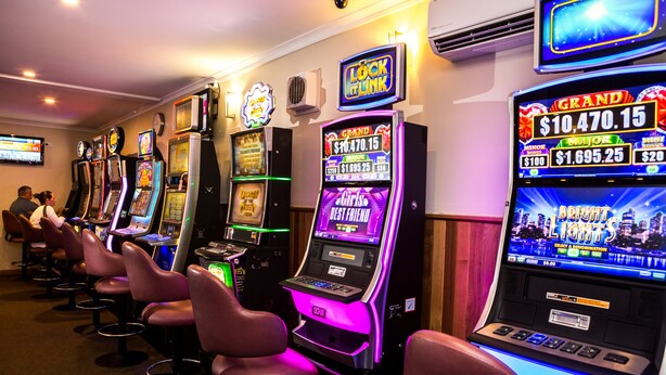 Fila de máquinas tragamonedas en un casino, con vista al horizonte de la ciudad de fondo.