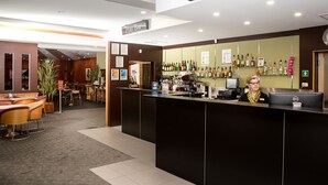 Un área de recepción con barra, asientos y una computadora.
