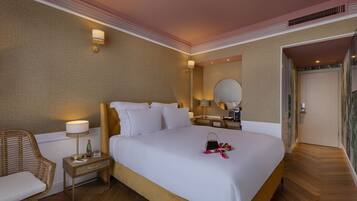 A hotel room with a large bed, a bedside table with a lamp, a chair, and a mirror.