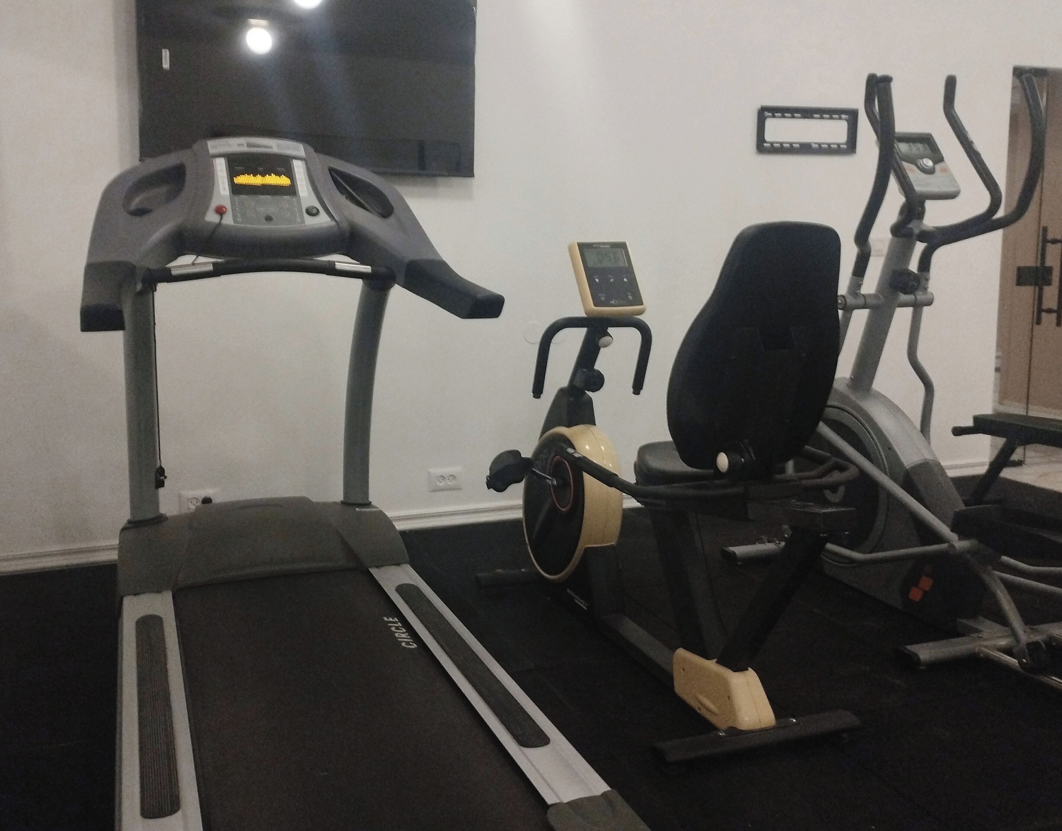 A gym with a treadmill, elliptical, and stationary bike.