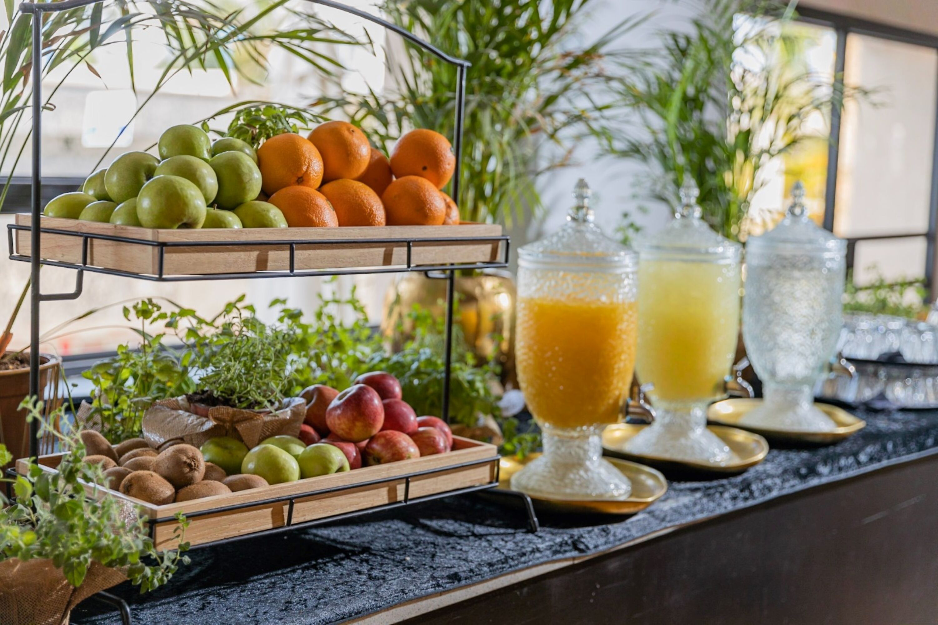 A fruit and juice display with a variety of fruits and two large glass containers of juice.