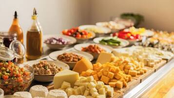 A buffet with various cheeses, fruits, and condiments.