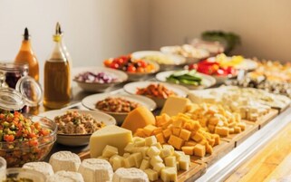 A buffet with various cheeses, fruits, and condiments.