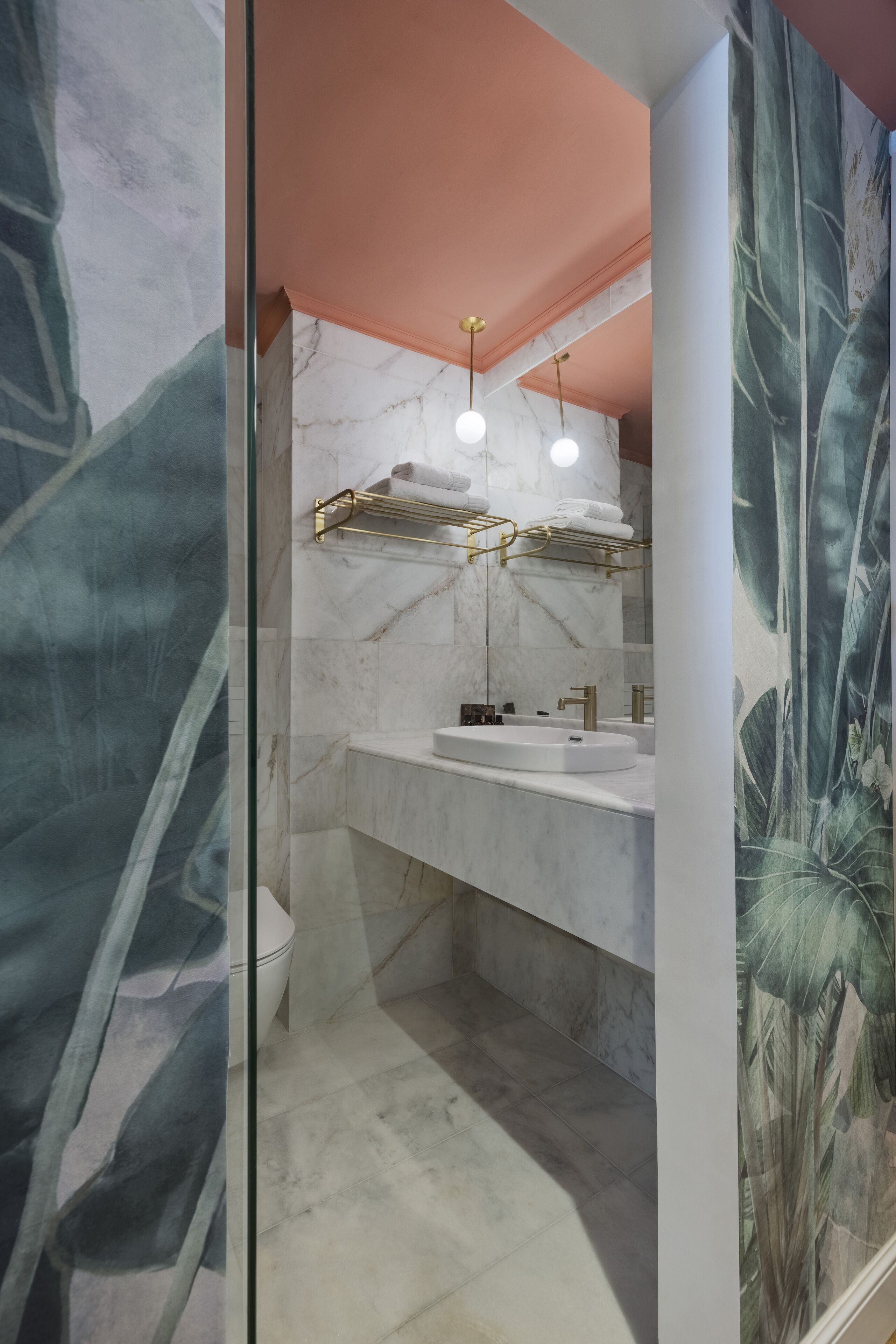 Ein modernes Badezimmer mit Marmorwaschbecken, goldenen Armaturen und einem großen Spiegel.