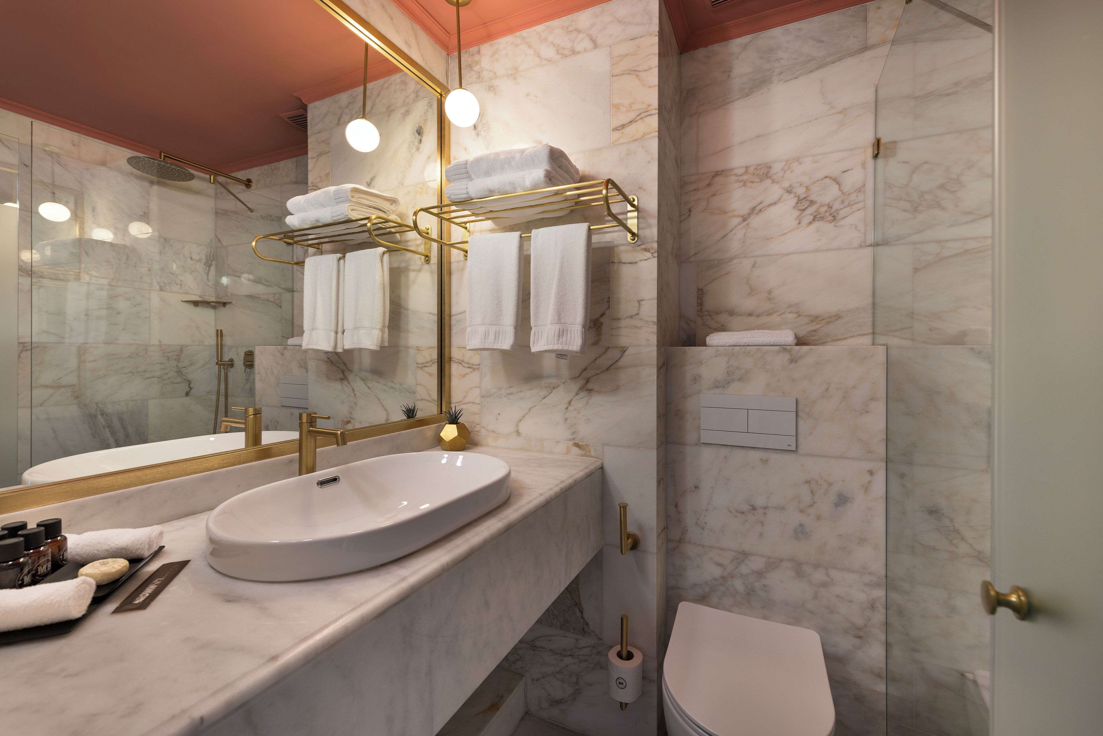 A modern bathroom with a marble vanity, a gold-framed mirror, and a glass-enclosed shower.