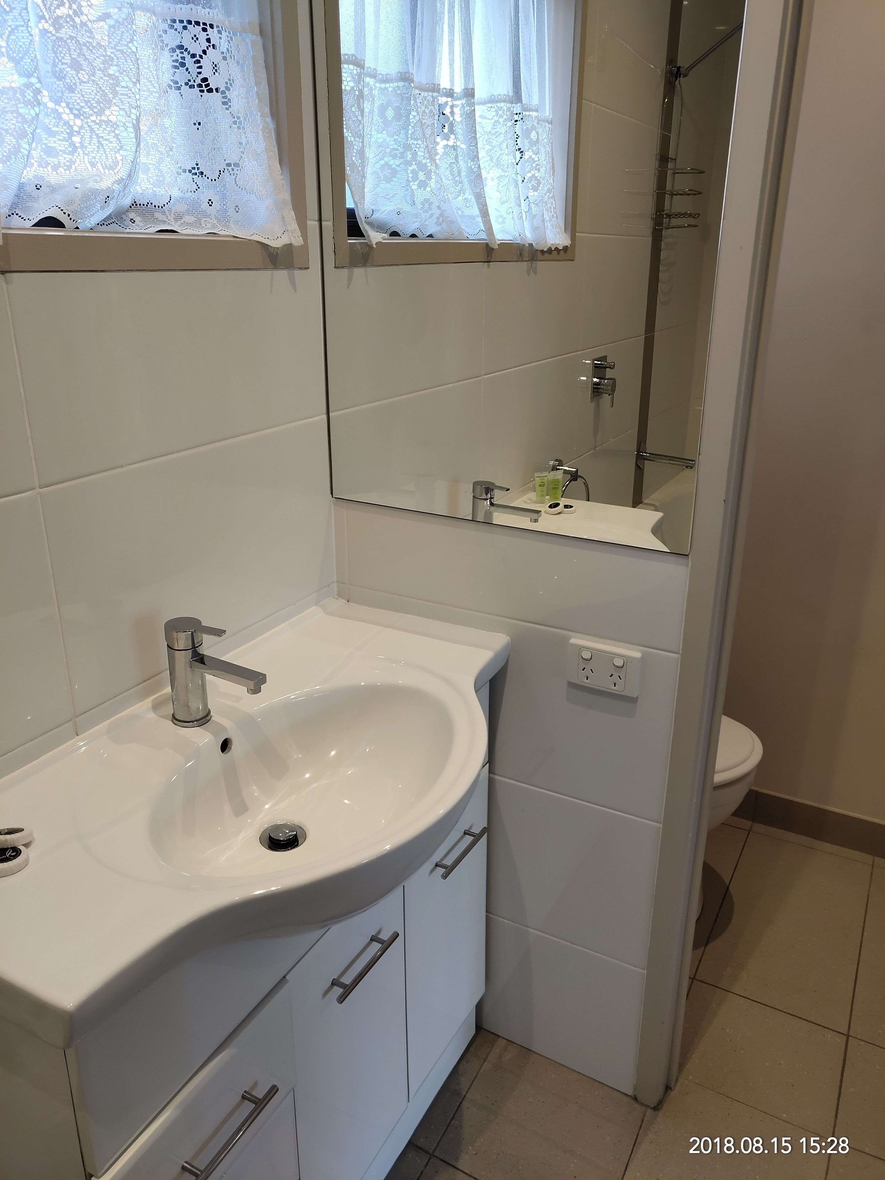 A bathroom with a white sink, mirror, and toilet.