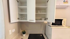 Una cocina compacta con armarios blancos, un microondas integrado y una pequeña encimera.