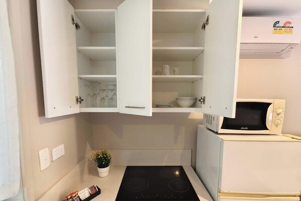 Una cocina compacta con armarios blancos, un microondas integrado y una pequeña encimera.