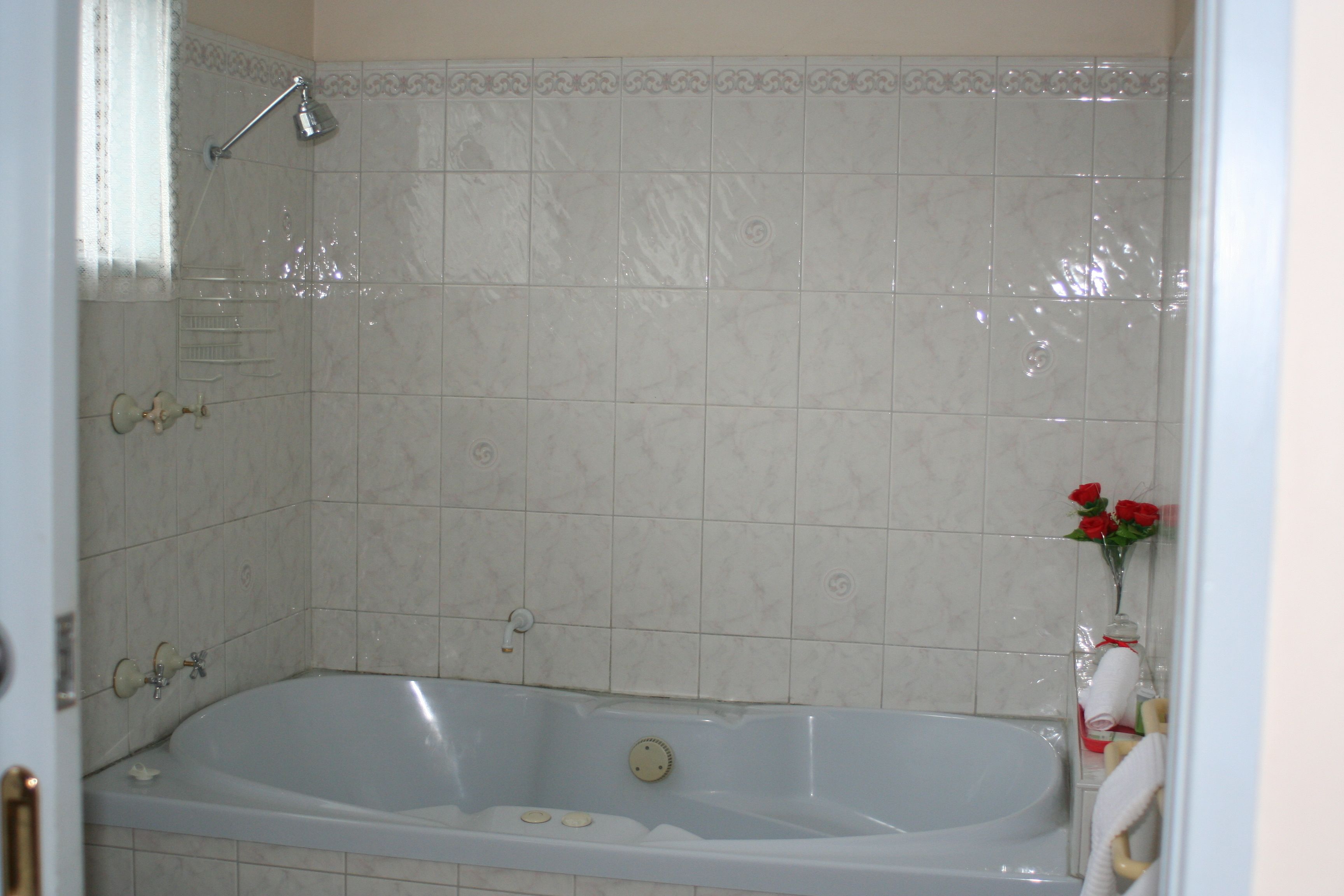 Une salle de bain avec une baignoire, une douche et un mur carrelé.