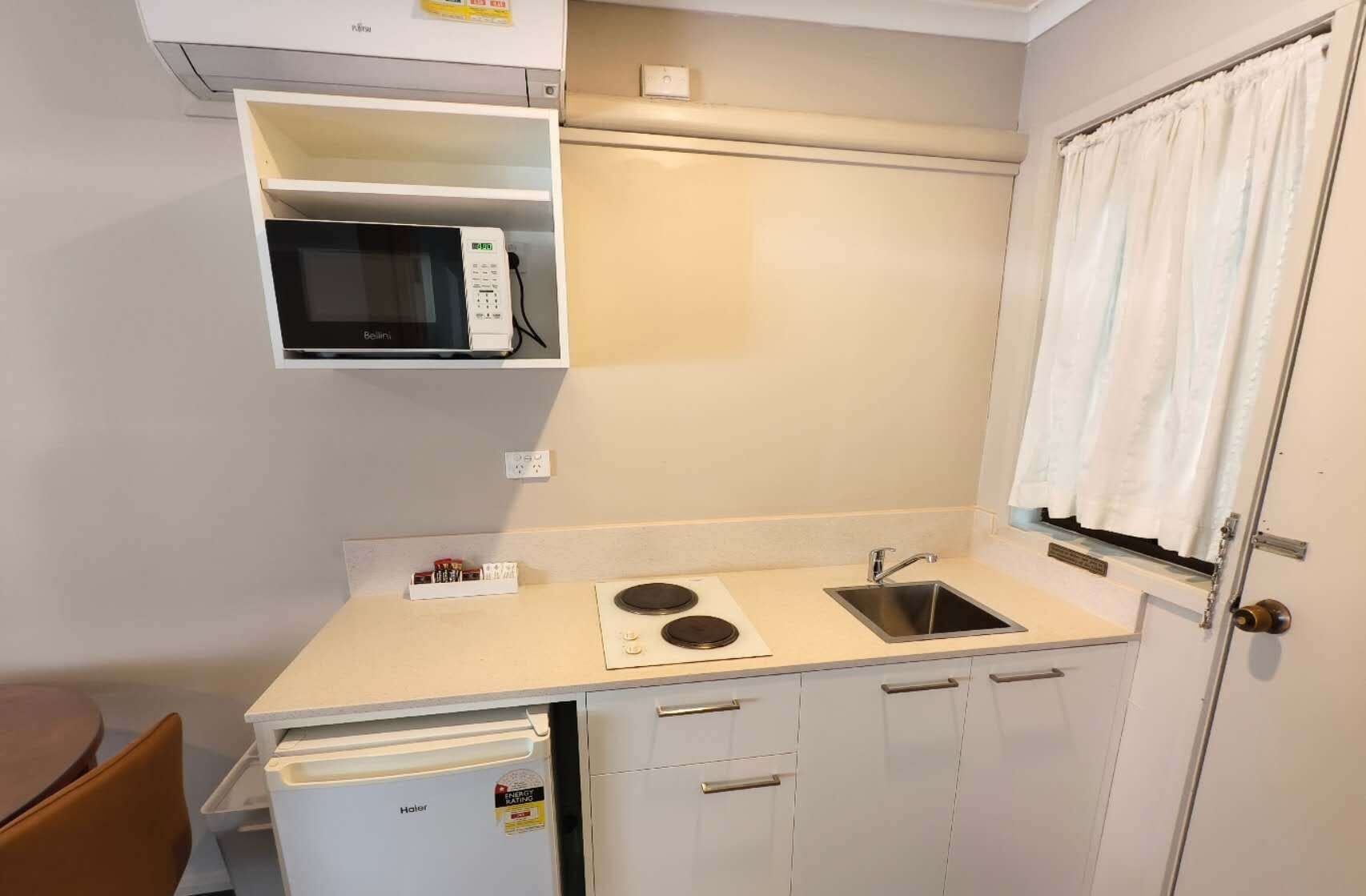 A compact kitchenette with a microwave, sink, and small refrigerator.