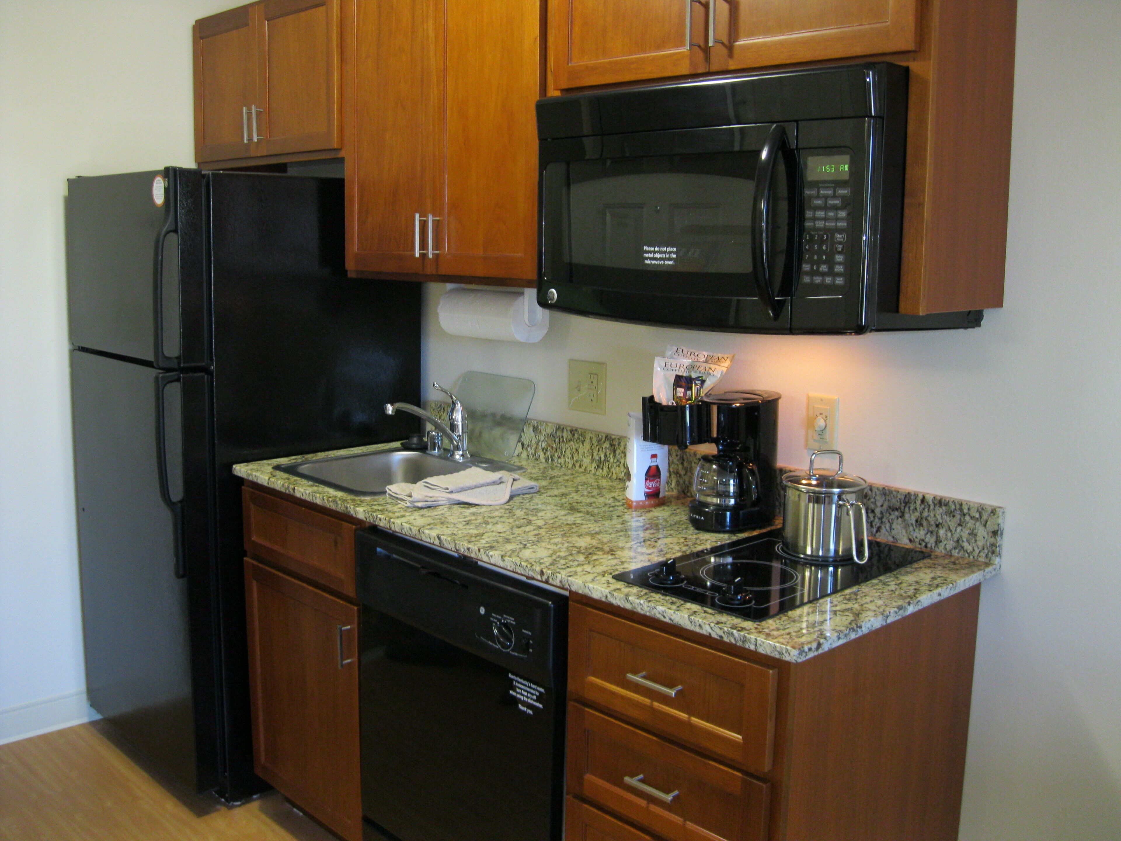 Cocina compacta equipada con refrigerador, microondas, cafetera y lavavajillas.