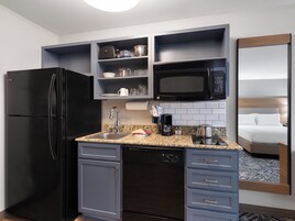 Cocina de hotel compacta con refrigerador, microondas, cafetera y pileta.