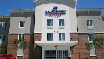 A hotel with a modern facade, a prominent entrance, and a parking area with a red car.