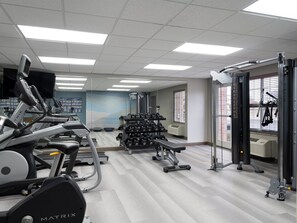 Uma academia com esteiras, halteres e aparelhos de musculação.