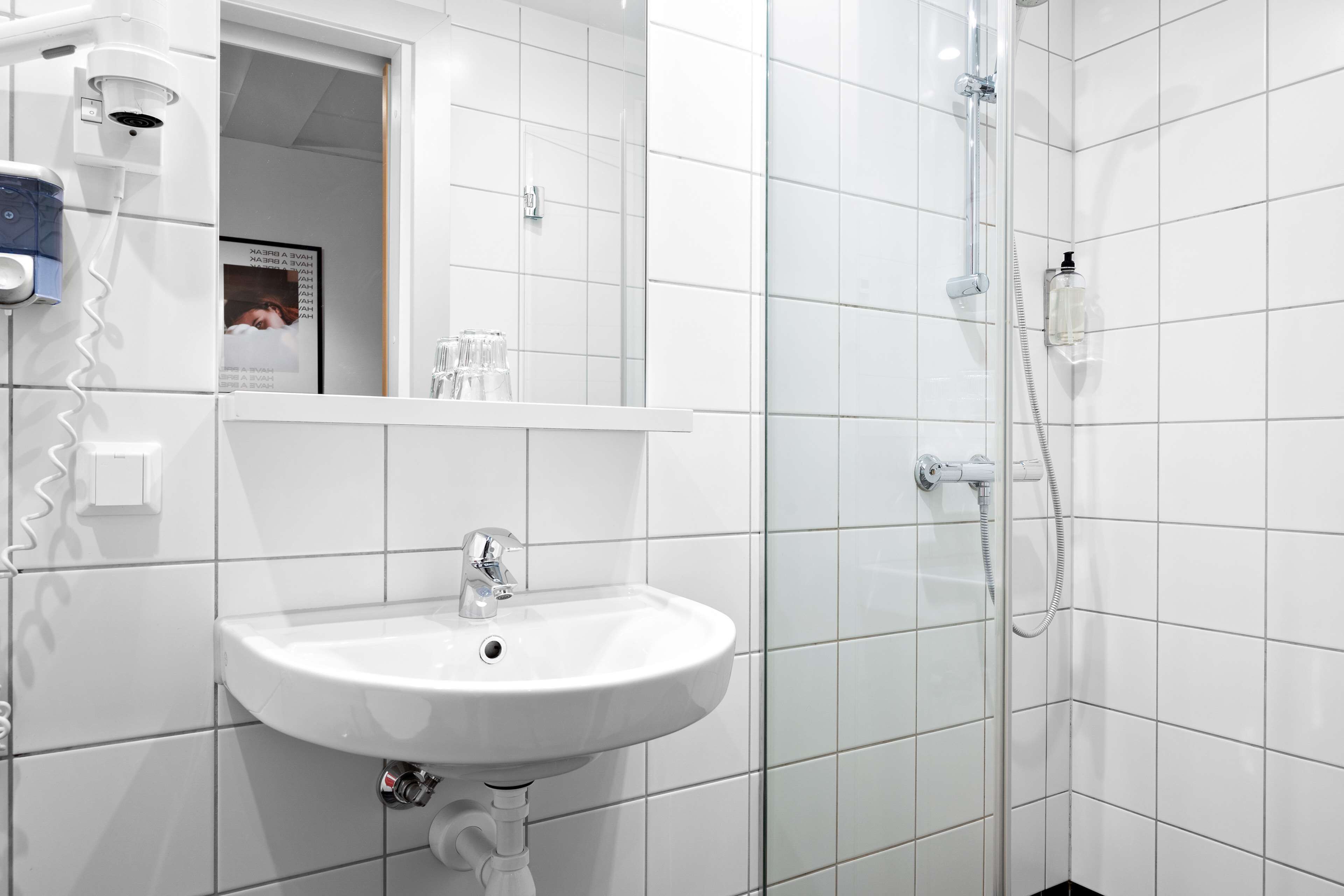 A bathroom with a white sink, a mirror, and a shower.