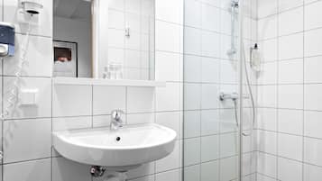 A bathroom with a white sink, a mirror, and a shower.