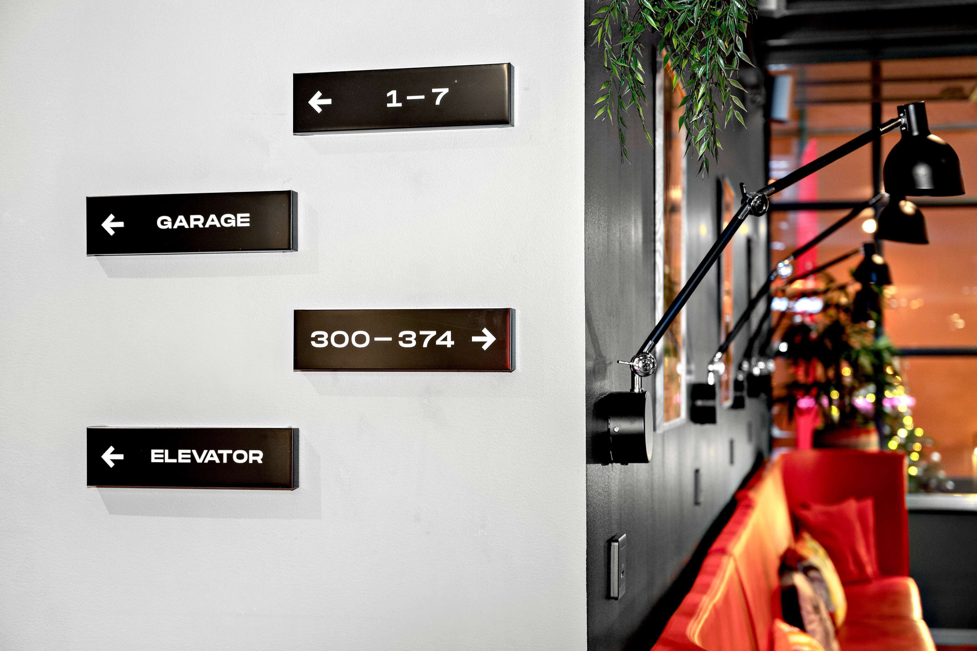 A wall with directional signs for a garage, elevator, and rooms 300-374.