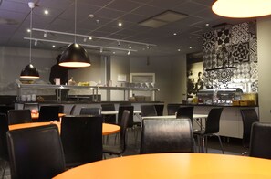 A modern restaurant with black chairs, orange tables, and pendant lighting. - Aiden by Best Western Stockholm City (Stockholm)