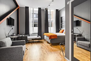 A modern hotel room with a bed, two armchairs, a desk, and a TV. - Aiden by Best Western Stockholm City (Stockholm)
