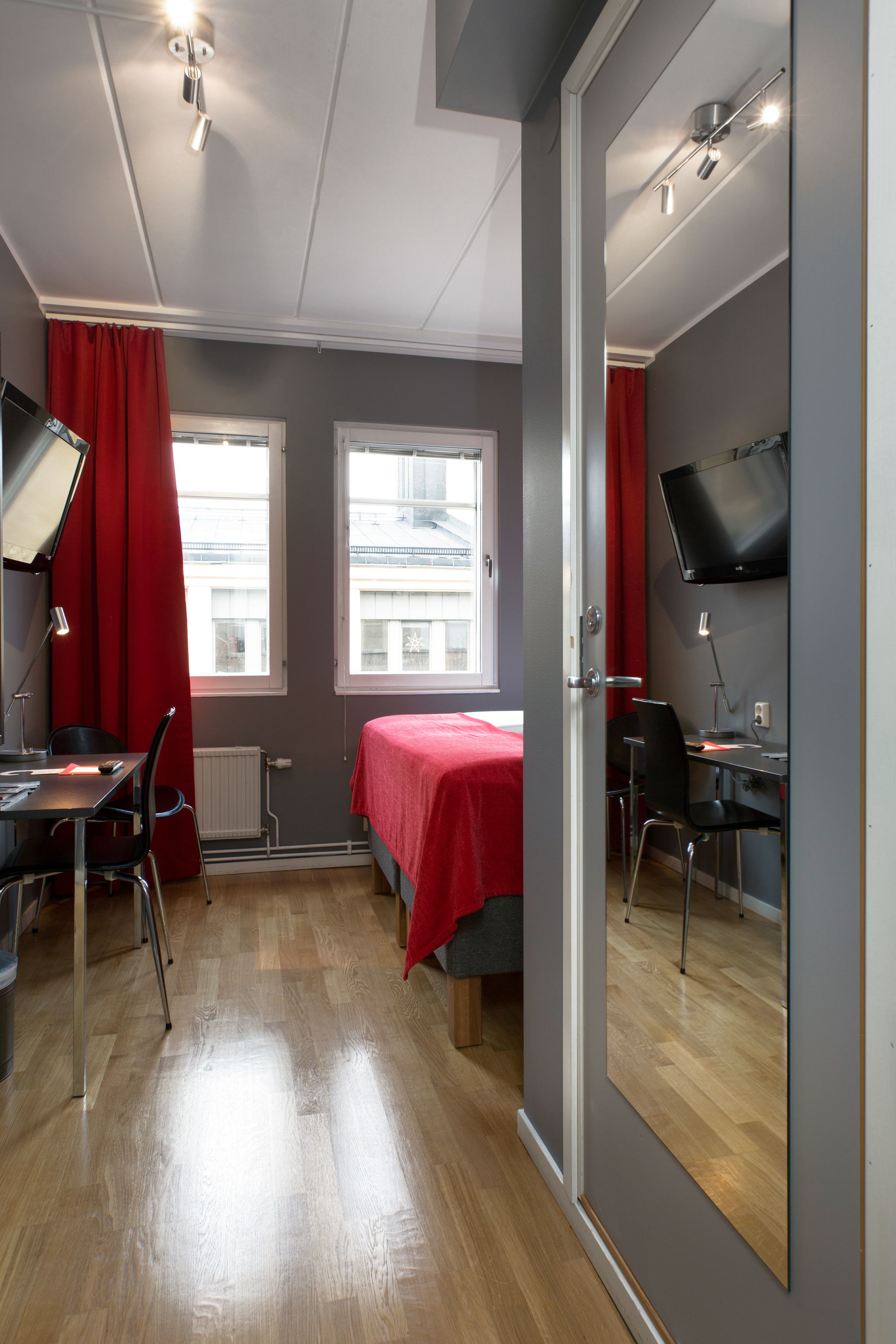 Una habitación con cama, escritorio, silla, televisor y ventana.