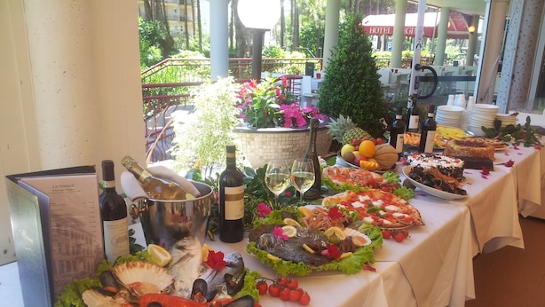 A table set with seafood, wine, and fruits, indicating a dining area with a view of the outdoors.