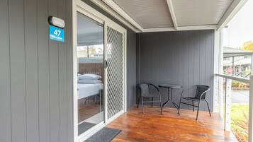 A room with a sliding glass door, a small table with two chairs, and a number sign indicating room 47.