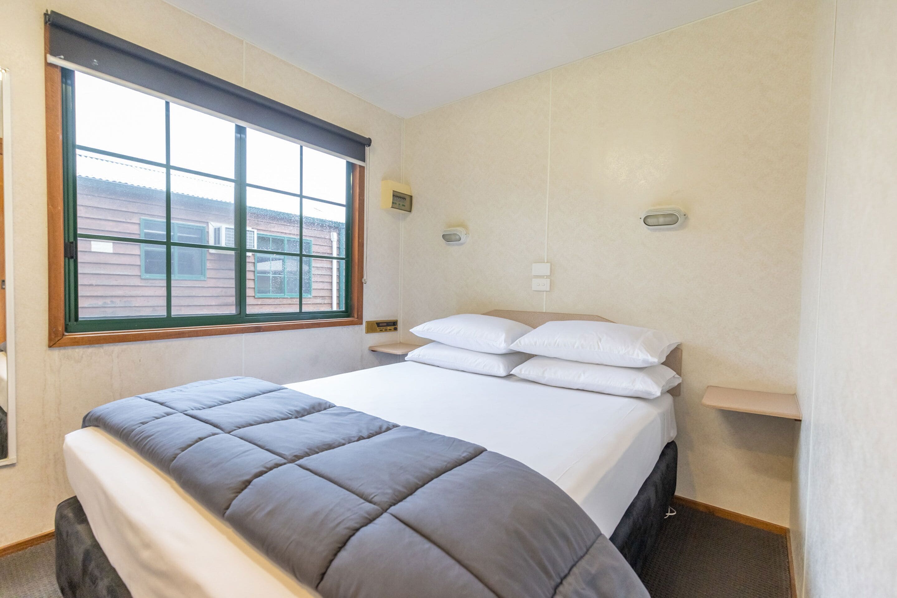Een slaapkamer met een groot bed, een raam en een klein nachtkastje.