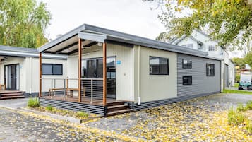A modern mobile home with a covered porch, large windows, and a number 45 sign.