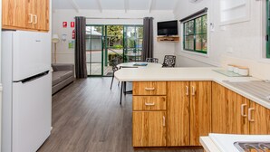 Een moderne keuken met houten kastjes, een ingebouwde kookplaat en een eethoek met een tafel en stoelen.