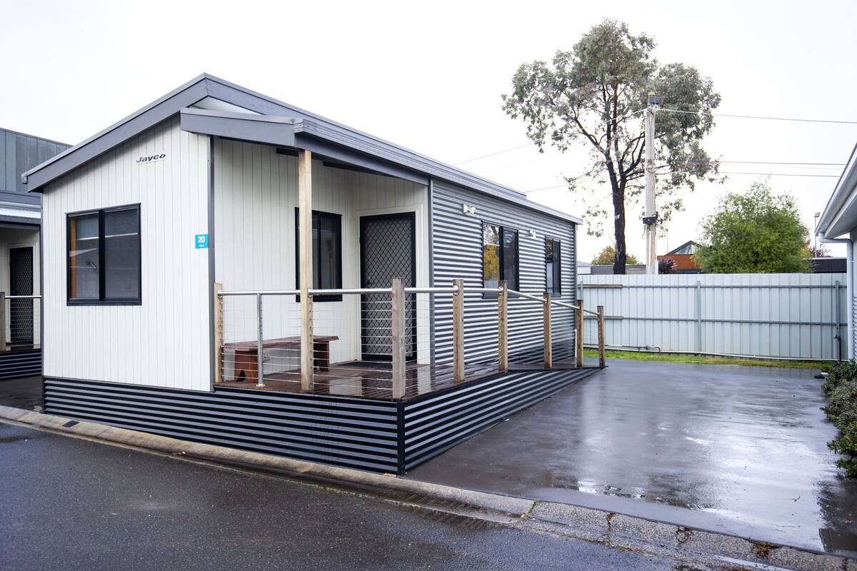 A single-story mobile home with a covered porch and a small outdoor seating area.