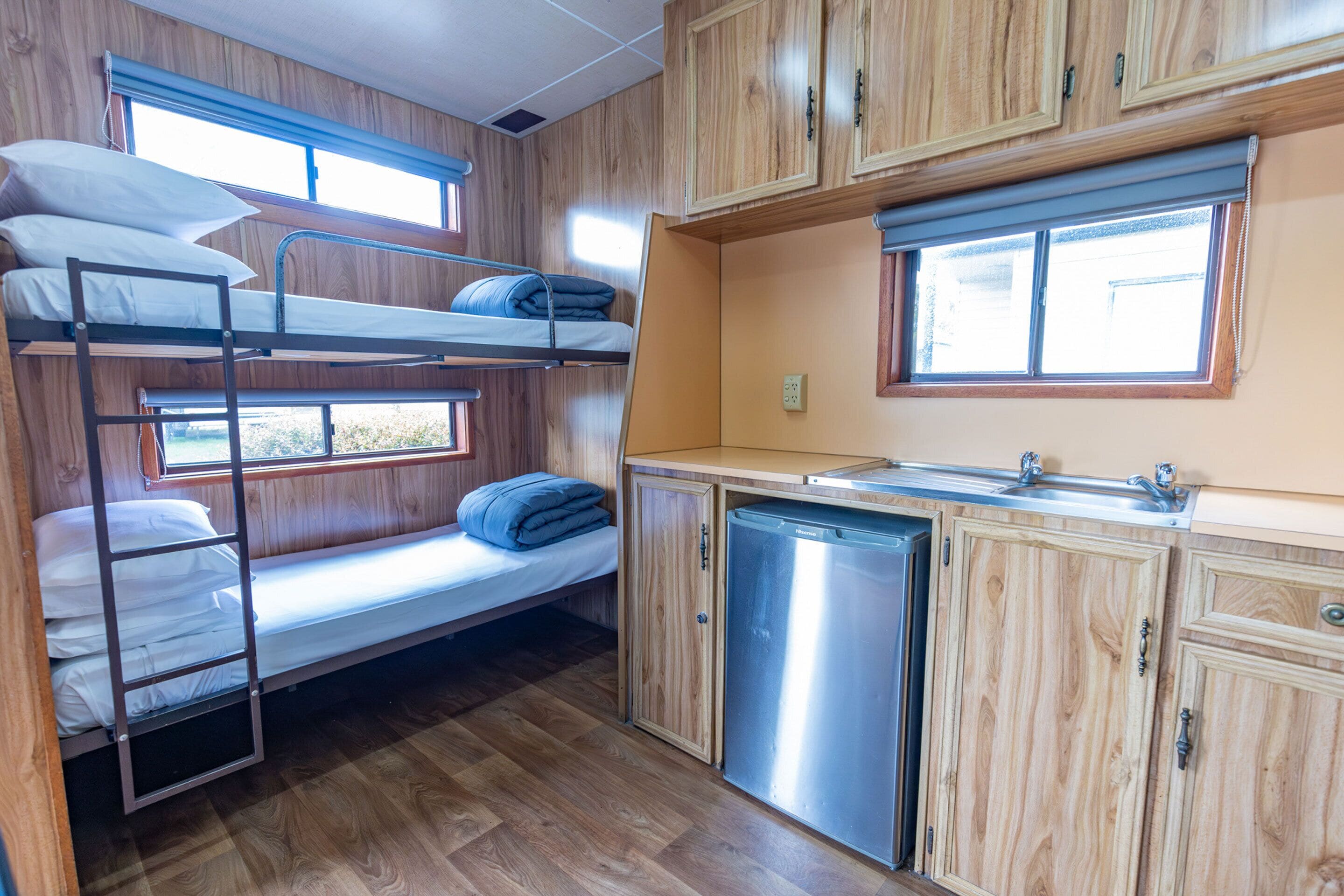 A compact RV kitchen with wooden cabinets, a sink, and a compact refrigerator.