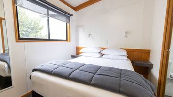 Un dormitorio con cama, mesita de noche, ventana y puerta.