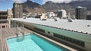 A poolside area with a view of mountains and buildings in the background. - Greenmarket Place Apartments (Cape Town)