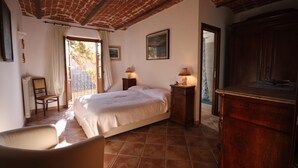 A bedroom with a bed, two bedside tables with lamps, a chair, a wooden cabinet, and a window with curtains. - Relais San Desiderio (Calliano)