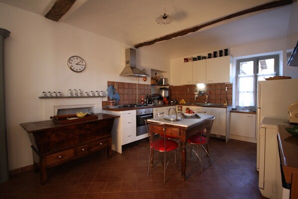 A kitchen with a wooden table, chairs, a stove, and cabinets.