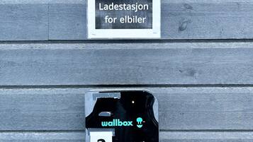 Parkeringstegn for elbil og en vægmonteret ladestation med nummer 2.