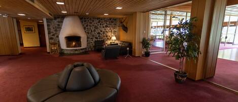 A spacious lobby with a stone wall, a fireplace, a leather sofa, and a potted plant.