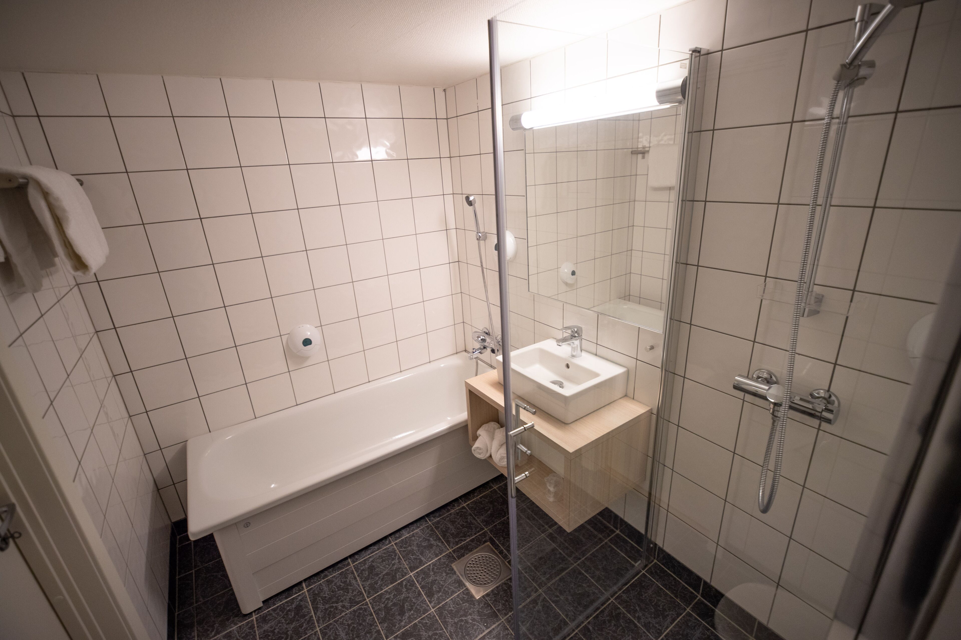 A modern bathroom with a bathtub, a sink, and a glass-enclosed shower area.