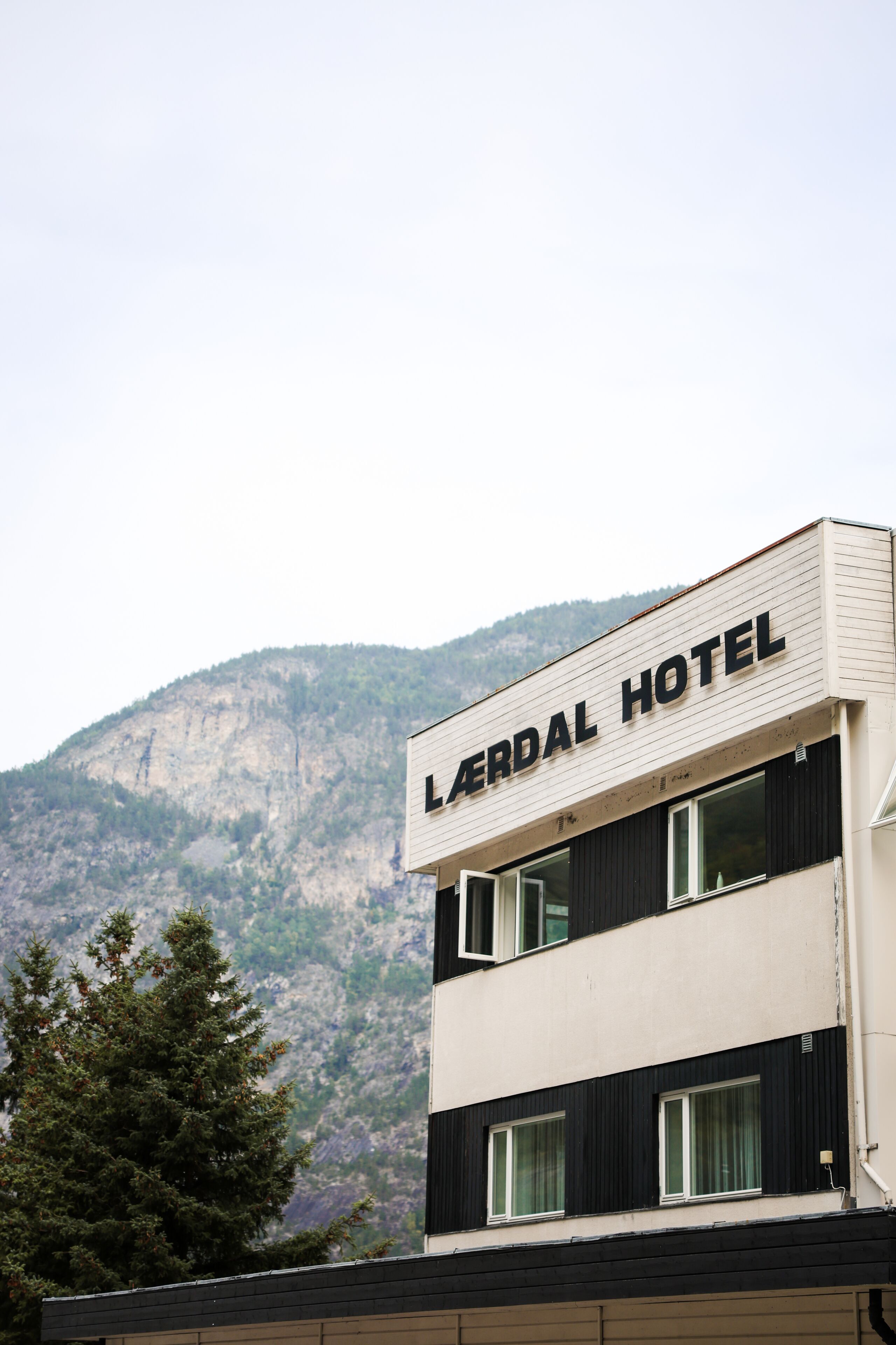 A hotel named 'Lerdal Hotel' with a two-story structure, large windows, and a mountainous backdrop.