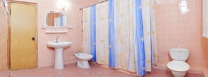 Un baño con lavamanos, bidé, inodoro y cortina de ducha.