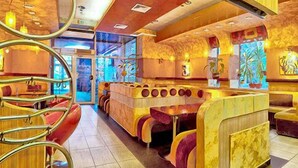Um restaurante com cabines e área de bar, com esquema de cores quentes e decoração na parede.