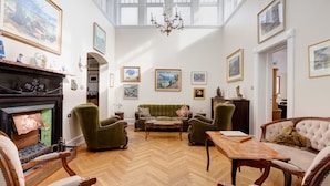 Una habitación amplia con suelo de espiga, chimenea, sofá y candelabro.