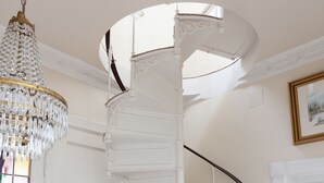 Una imponente escalera con barandales blancos de diseño intrincado y un candelabro de cristal.