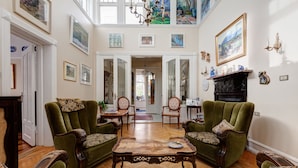 Un salón espacioso con techos altos, chimenea y vistas al comedor.