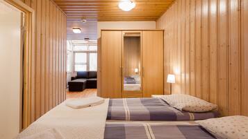 A bedroom with two beds, wooden walls, a wardrobe, and a mirror.